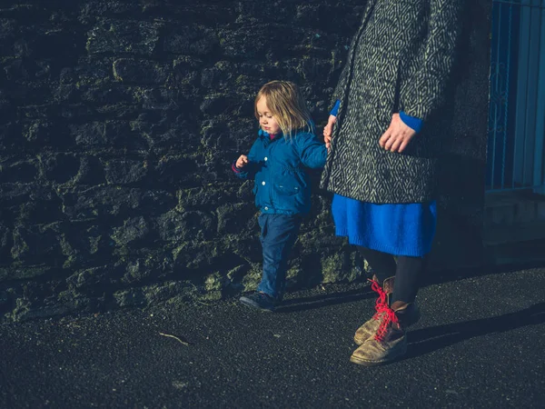 Madre y niño pequeño tomados de la mano a pie en invierno — Foto de Stock