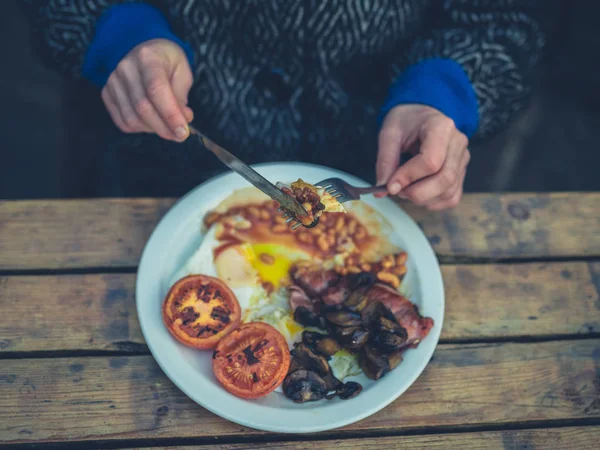 Молода жінка їсть англійський сніданок у кафе — стокове фото