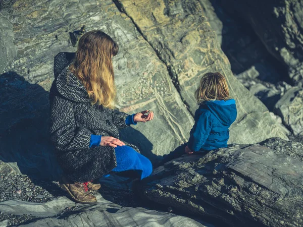 Moeder zittend op rots met toddle rin winter — Stockfoto
