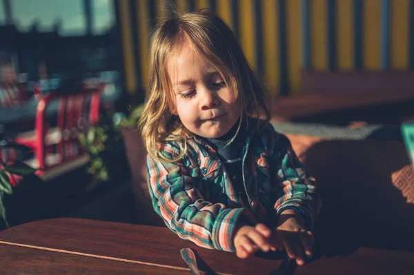 Little toddler sitting at cafe table with cutlery — Stock Photo, Image