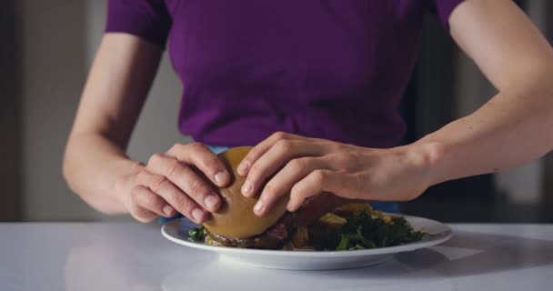 若い女性がフライドポテトとバーガーを食べています — ストック動画