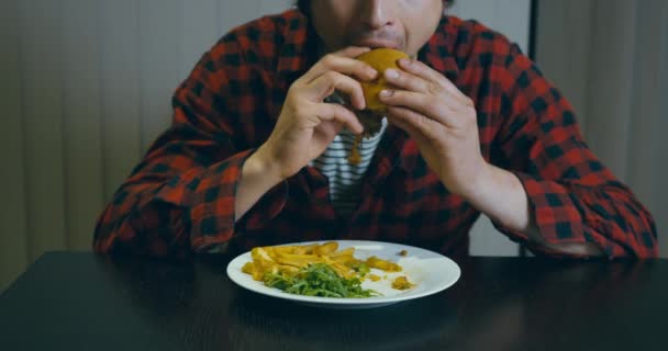 一个穿着嬉皮士衬衫的年轻人正在吃汉堡包 — 图库视频影像