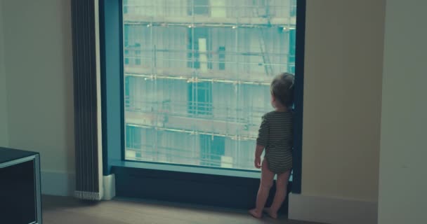 Little boy standing by window in city apartment — Stock Video