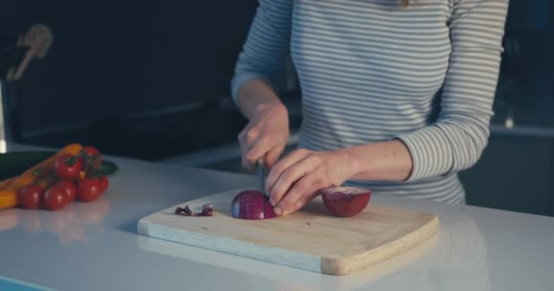 Jonge vrouw hakken uien in haar keuken — Stockvideo