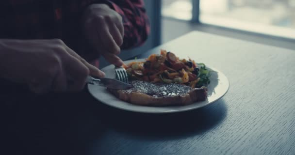 Jovem comendo bife pela janela — Vídeo de Stock