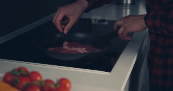 Młody człowiek gotuje stek i pali sobie rękę. — Wideo stockowe