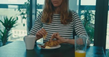 Ağır çekimde kruvasan yiyen bir kadın.