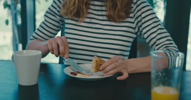 Mujer joven comiendo croissant y tomando café — Vídeos de Stock