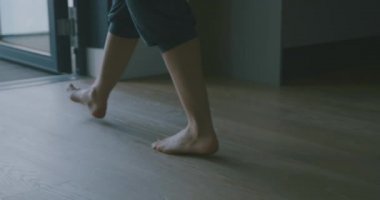 Spor arabalı çıplak ayaklı genç kadın balkona doğru yürüyor.