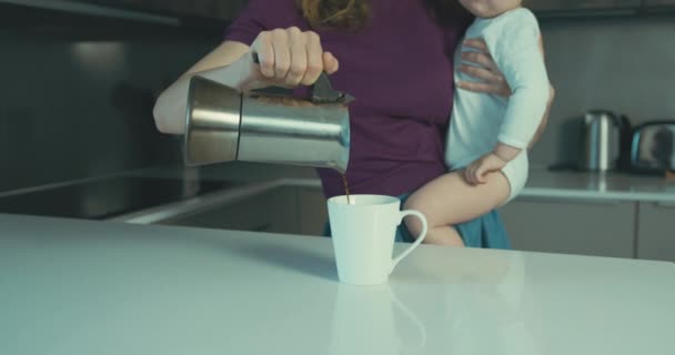 若い母親は台所にいる彼女の幼児を保持し コーヒーを注ぎます — ストック動画