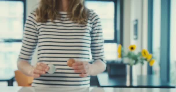 现代厨房里的一位年轻女士拿着一只棕色的鸡蛋和一只蓝色的鸡蛋来展示两者的不同 — 图库视频影像