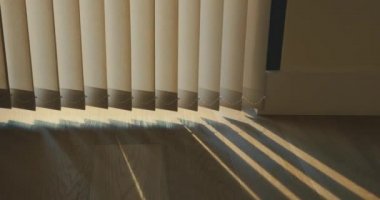 Şehirdeki bir dairenin perdeleri gün batımında uzun gölgeler bırakır.