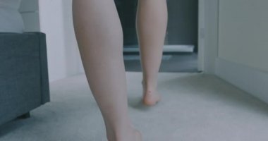 Genç bir kadın yatağından kalkıyor ve banyoya giriyor, bir havlu giyiyor ve duşa giriyor. El bilgisayarı ağır çekim.