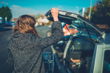 Genç bir kadın kışın alışverişini steyşın arabasına yüklüyor.