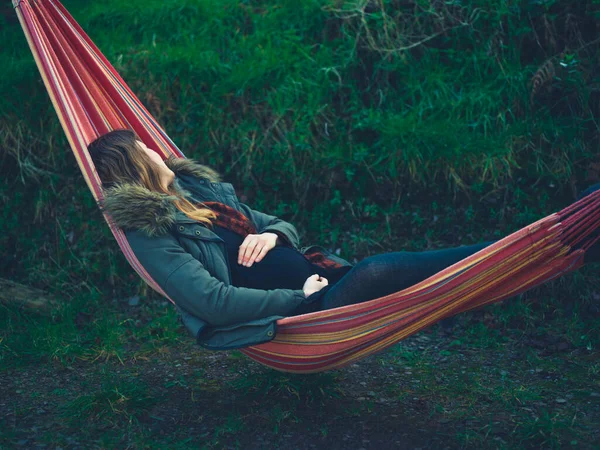 妊娠中の若い女性は冬の日にハンモックで庭で寝ています — ストック写真