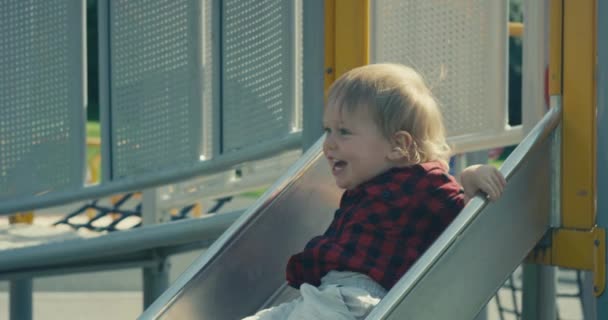 Ein Kleiner Junge Geht Auf Dem Spielplatz Die Rutsche Hinunter — Stockvideo