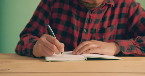 ノートに緑の画面に反対する若い男が書いている — ストック動画