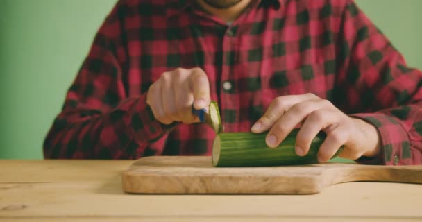 Een Jonge Man Snijdt Snijdt Een Komkommer Een Groen Scherm — Stockvideo