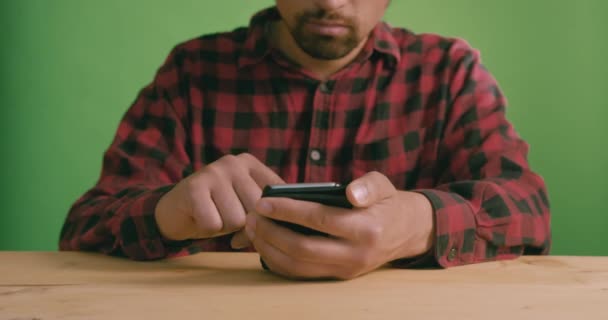 Jovem Contra Uma Tela Verde Está Usando Smartphone — Vídeo de Stock