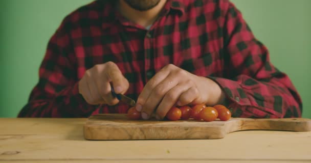 若い男はスローモーションで緑の画面にトマトを切断しています — ストック動画