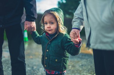 Küçük bir anaokulu öğrencisi kışın dışarıda büyükannesi ve büyükbabasıyla el ele yürüyor.