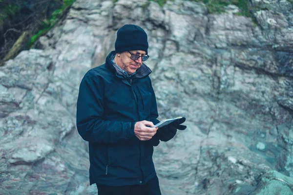 A mature man is studying a map in the mountains in winter