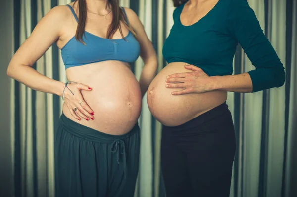 两个穿着运动服的孕妇正在比较她们的腹部 — 图库照片