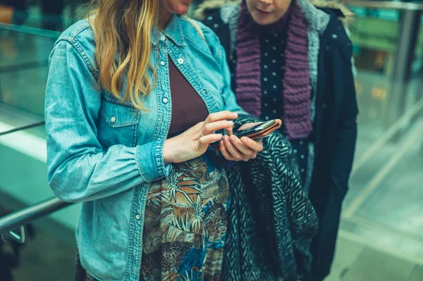 Zwei Junge Frauen Schauen Einem Einkaufszentrum Auf Ein Smartphone — Stockfoto