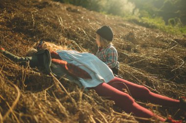 Genç bir anne, anaokulu öğrencisi yanında otururken bir tarlada yatıyor.