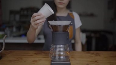 Kahve ve bira Kupası için kaynar su dökerek çaydanlık gelen kadın barista koyarak görünümü rendelenmiş