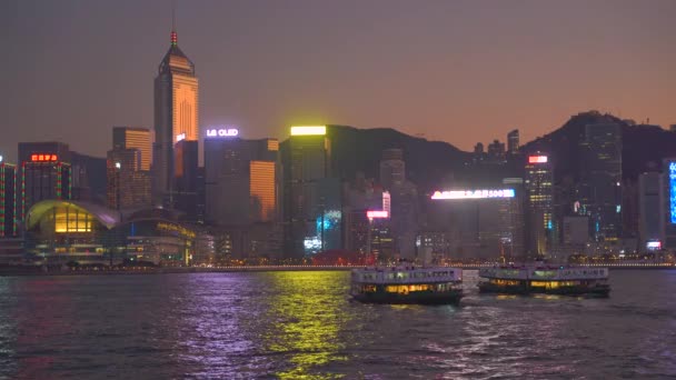 Hong Kong, Čína - 06. 12. 2019: 4k Victoria Harbour s panorama a turistickými loděmi v noci — Stock video