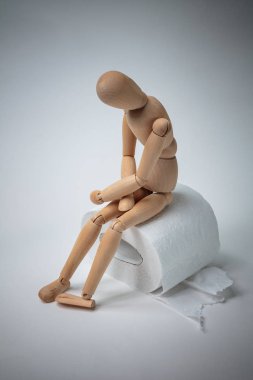 Bir rulo tuvalet kağıdının üzerinde oturmuş midesini tutan, ishal, karın ağrısı, gıda zehirlenmesi, bağırsak enfeksiyonu...