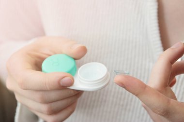 Kızın elinde kontakt lensler ve parmağında lens var.