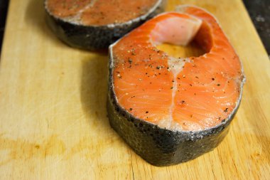 Somon steak bir ahşap tahta üzerinde kaba tuz ve biber ile