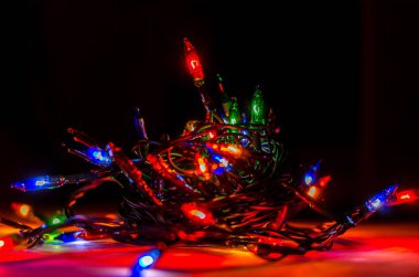 Karanlık bir odada Noel çelenginden ışıklar, yanan ampuller, kış Noel havası, kapat.