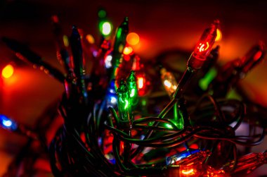 Karanlık bir odada Noel çelenginden ışıklar, yanan ampuller, kış Noel havası, kapat.