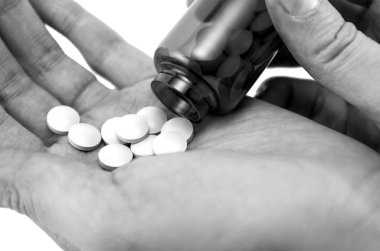 Elinde isilik olan bir hapın siyah beyaz görüntüsü, ilaç konsepti herkes için değil, ilacın yüksek maliyeti.