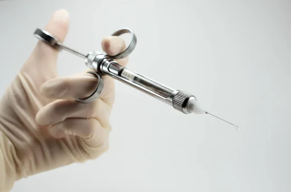 Beyaz arka planda lokal anestezi için servis şırıngası olan el doktoru.
