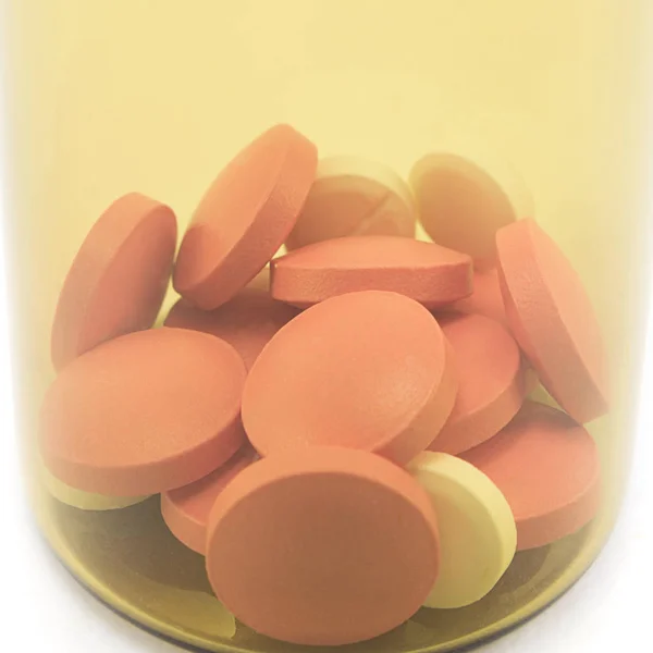 錠剤や薬の入った錠剤の黄色のガラス瓶を白い背景に閉じ込めマクロ — ストック写真