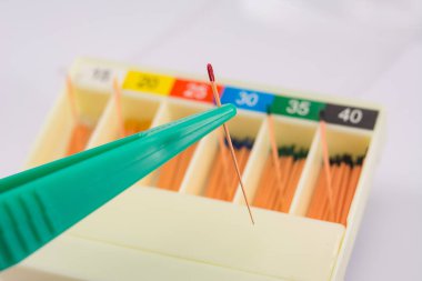 Kök kanal dolguları için farklı boyutlarda gutta-percha pimleri, cımbızla yakın çekim, endodontik dolgular için malzeme.