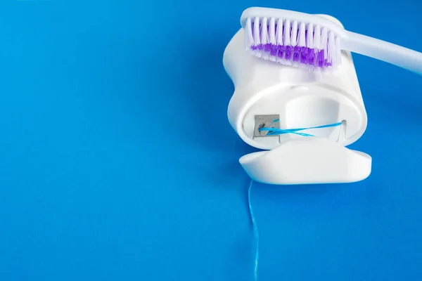 蓝色背景的牙线和牙刷 口腔护理的概念 防止蛀牙 — 图库照片