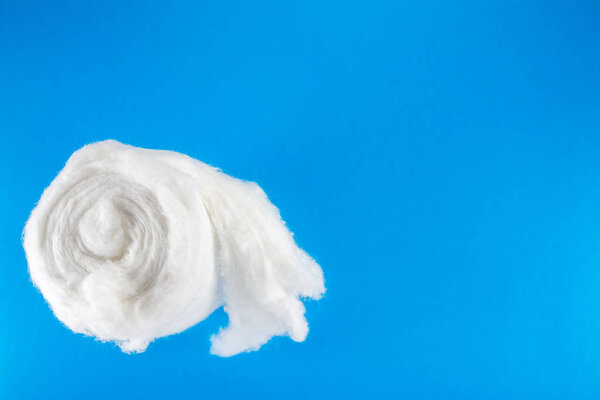 большой рулон медицинского хлопка на синем фоне крупным планом
