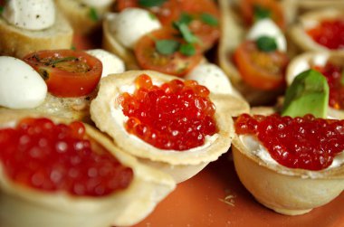 Kırmızı somon havyarlı tartlar, taze somon dilimleri, peynir, avokado ve domates.