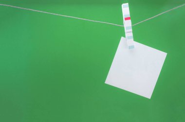 Yeşil arkaplanda çamaşır mandalları üzerine beyaz kağıt kağıtlar, maket yap, boşluk kopyala