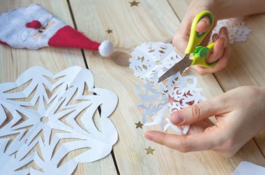 Kız, kağıttan yapılmış ev yapımı kar taneleri yapıyor. Yeni yıla hazırlanıyor. Noel, ev dekorasyonu.