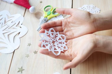 Kız, kağıttan yapılmış ev yapımı kar taneleri yapıyor. Yeni yıla hazırlanıyor. Noel, ev dekorasyonu.