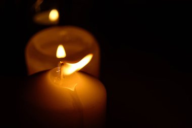 Siyah arka planda yanan mumların alevi makroyu kapatır.