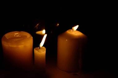 Siyah arka planda yanan mumların alevi makroyu kapatır.