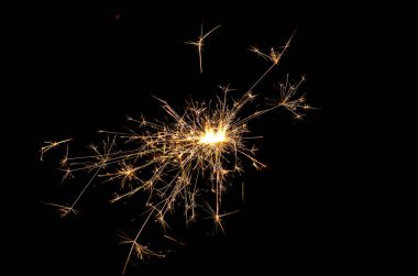 O, simsiyah bir zemin üzerinde kıvılcımlar saçar ve uçuşur.