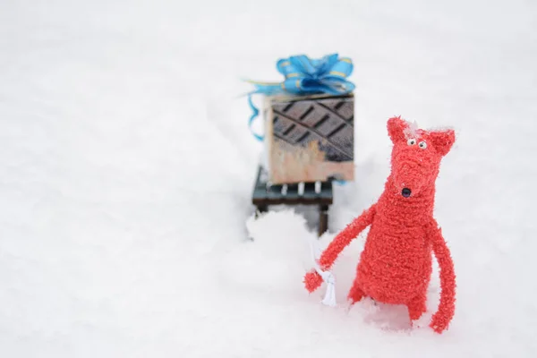 Красная Игрушечная Лиса Несет Упакованный Рождественский Подарок Санках Снегу Снегопад — стоковое фото